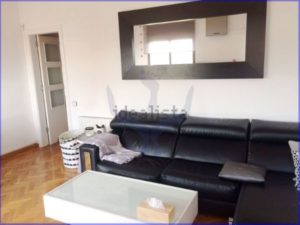 A luminous 75 m2 apartment in Barcelona with a black couch, coffee table and mirror.