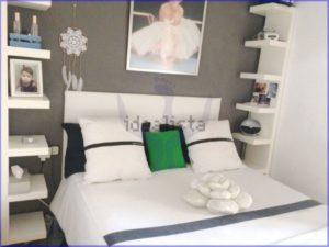 A luminous 75 m2 bedroom with a white bed and a picture on the wall in Barcelona.
