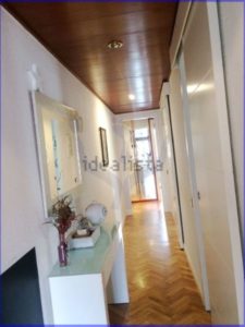 A luminous hallway with white walls and wooden floors in a 75 m2 apartment in Barcelona.