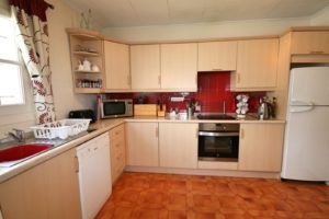 A kitchen in a semi detached Villa near Alicante with a red tile floor.