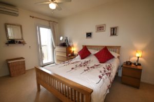 A semi detached Villa near Alicante furnished with a bed, dresser, and a ceiling fan in the bedroom.