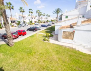 An aerial view of a residential area with parked cars, palm trees, and semi-detached villas near Alicante.