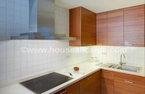 A 128m2 apartment in the center of Alicante with a kitchen featuring wooden cabinets and a sink.