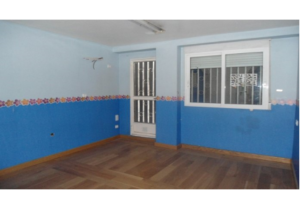 A spacious room with blue walls and a wooden floor, located in the centre of Valencia, priced at less than 1000€/m2.