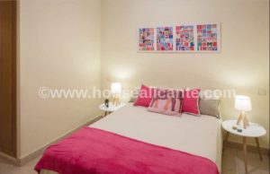 A 128m2 apartment with a bedroom featuring a pink comforter and pictures on the wall, located in the center of Alicante.