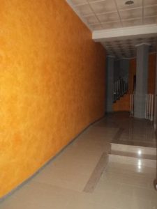 A hallway with an orange wall and stairs.