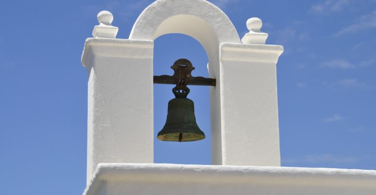 A Spanish bank's white building with a bell on top available for sale.