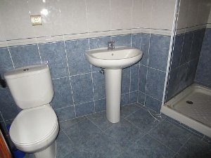 A LAREDO apartment with a blue tiled bathroom consisting of a toilet and sink.