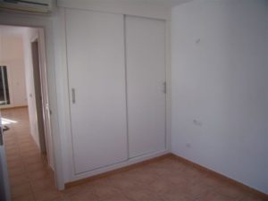 A white room with a tiled floor and a white door.