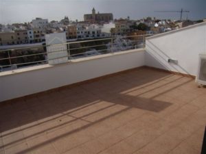 A tiled floor balcony in the Centre of Menorca with a view of the city.