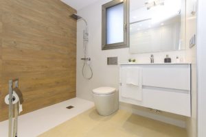 A white bathroom with a wooden wall in a villa for sale in Villamartín - Orihuela Costa.