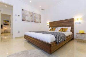 A white bed and wooden headboard in a villa for sale in Villamartín - Orihuela Costa.
