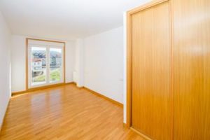 An empty Cesullas room with wooden floors and a sliding door.