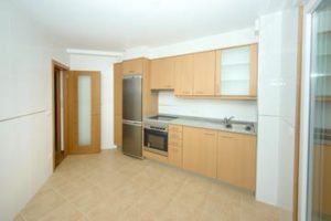 A kitchen with wooden cabinets and stainless steel appliances in a newly built building on the market.
