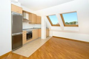 An empty newbuilding kitchen with wooden floors and a skylight.