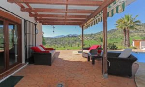 Detached villa for sale in Coín featuring a patio with wicker furniture and mountain views.