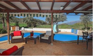 Detached Villa for sale in Coín featuring a patio with furniture and a swimming pool.