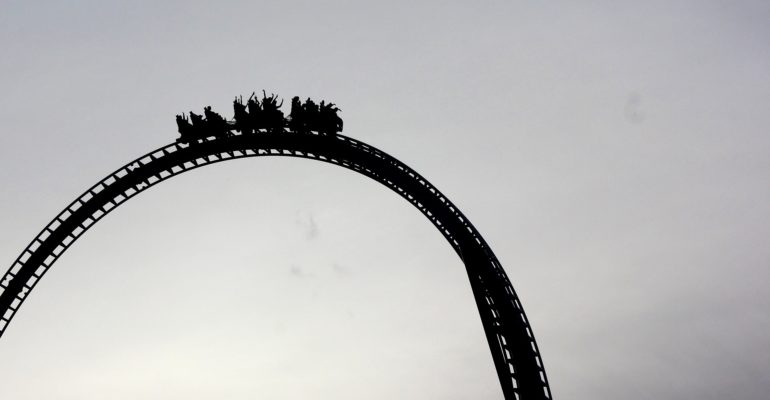 A roller coaster in a Spanish children's park on a cloudy day.