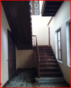 An empty room in a wonderful manor with wooden stairs and a window, undergoing some repair works.