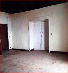 An elegant manor with wooden floors and a door, in need of repair works.