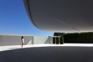 A woman stylishly poses in front of her dream house in Spain, designed by her architect.