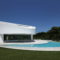 A dream house in Spain featuring a white exterior and a pool in front.