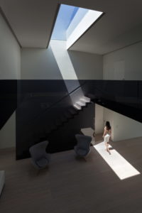 A woman is standing in a architect-designed room with a skylight, in her dream house in Spain.