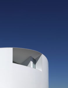A white architect-designed dream house in Spain with a blue sky behind it.