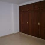 An empty room with wooden cupboards, tiled floor, located in a terraced house in Tenerife.