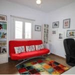 Detached villa for sale in Tolox with a living room featuring a red couch and bookshelves.