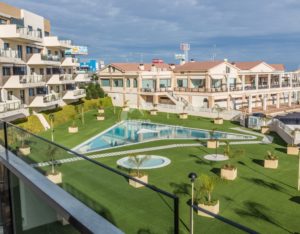 A luxury apartment complex in Costa Blanca South featuring a swimming pool and lawn.