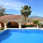 A detached villa in Mijas Costa with a swimming pool overlooking mountains.