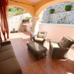 A detached villa in Mijas Costa with a patio featuring wicker furniture and a pool.