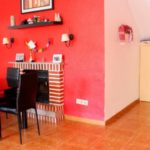 A Villamartin townhouse in Orihuela Costa with a living room featuring red walls and a table and chairs, priced under 100.000€.