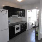 A beautiful 3 bedroom apartment with a small kitchen featuring white cabinets and black appliances in Tenerife, Los Cristianos.