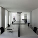 A renovated office in Spain with white walls, black desks, and chairs.