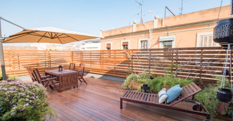 A Barcelona property investment featuring a wooden deck with a table and chairs.