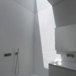 A white bathroom with a skylight over the sink.