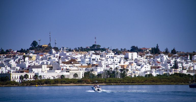 A property finder locates a boat in the water near a city on the Costa de la Luz.