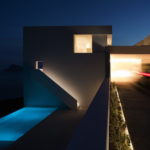 A modern house lit up at night.