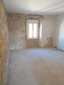 A renovated room with a stone wall and a window, available for sale in Costa Blanca.