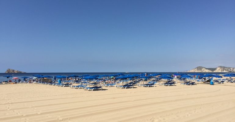 A beach with renovated chairs and umbrellas on the sand in Costa Blanca.