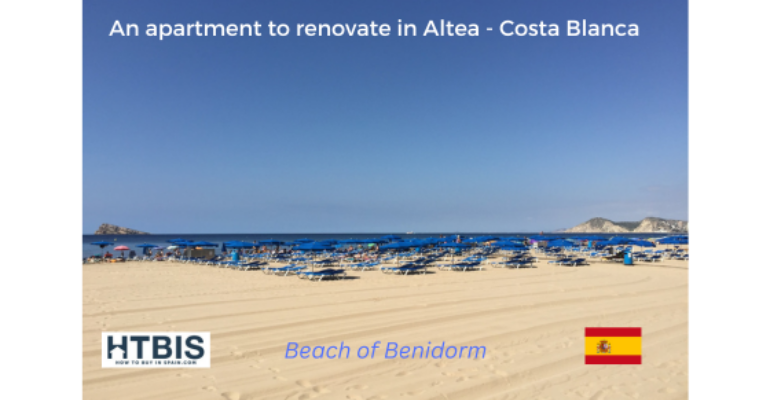 View of Benidorm beach with numerous blue sunbeds and umbrellas on the sand. Text on the image mentions an apartment to renovate in Altea, Costa Blanca. Flags and logos are also visible, hinting at Costa Blanca property for sale opportunities.