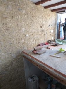 A man is renovating a stone wall in a room.