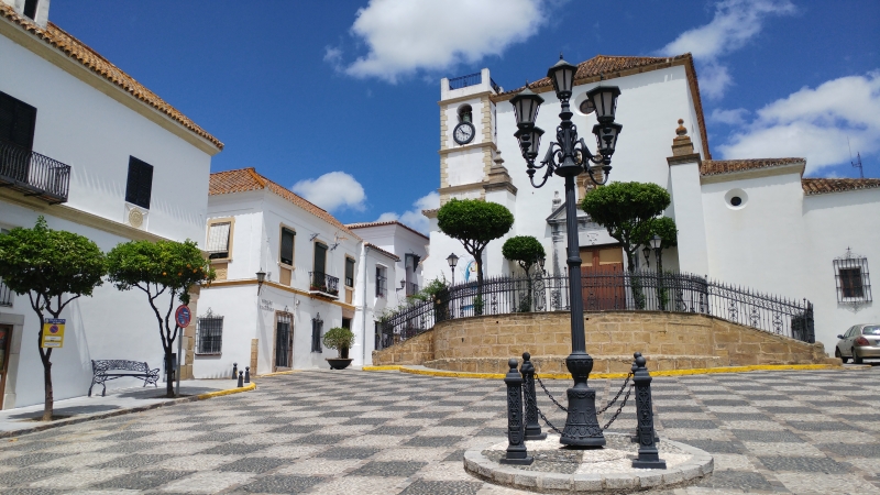 A street with a clock tower and new build white buildings in Cadiz, San Roque.