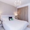 A bedroom with a white bed and a chandelier in a New build penthouse Cadiz.