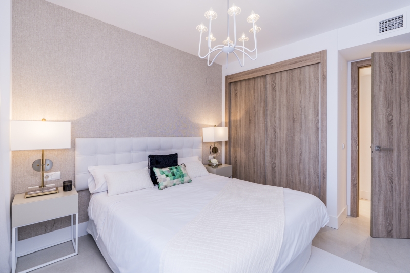 A bedroom with a white bed and a chandelier in a New build penthouse Cadiz.
