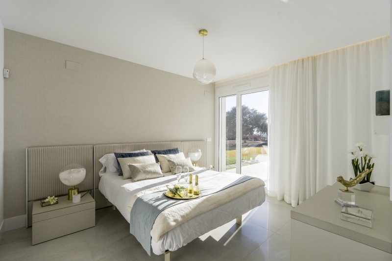 A new build penthouse in Cadiz with a white bed and a sliding glass door.