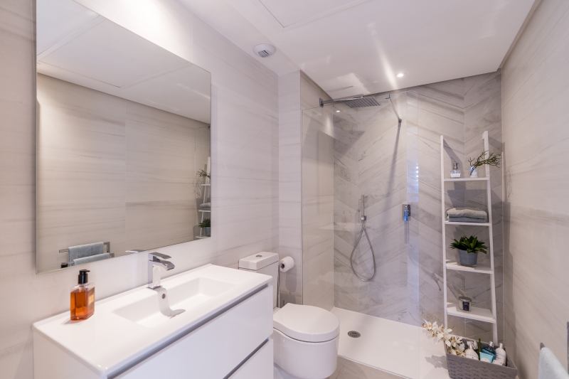 A modern white bathroom with a toilet, sink and mirror in a new build penthouse in San Roque.