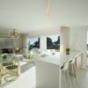 A white kitchen and living room with a view of the golf course in a San Roque New Build apartment.
